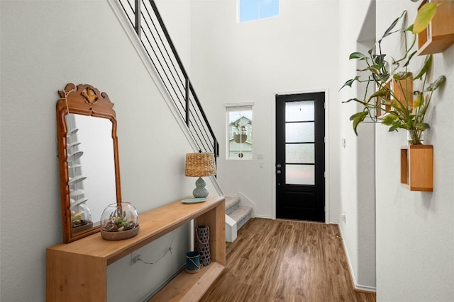 interior space with a towering ceiling, stairs, and wood finished floors