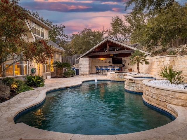 view of swimming pool featuring an in ground hot tub, pool water feature, exterior bar, and a patio