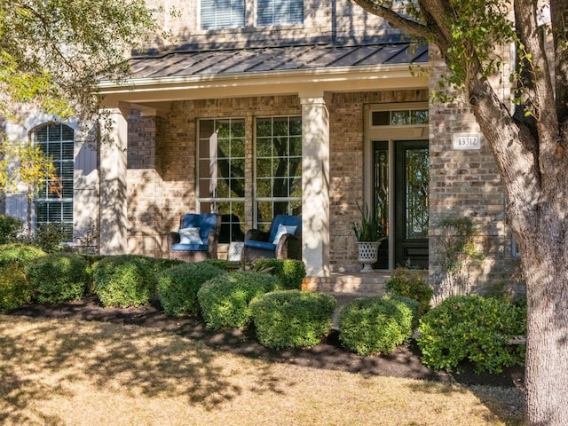 13312 Country Lake Dr, Austin, TX 78732 - view of exterior entry featuring a standing seam roof, brick siding, metal roof, and a porch