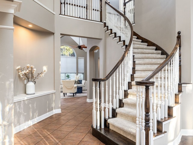 stairway featuring tile patterned flooring, ceiling fan, and a high ceiling