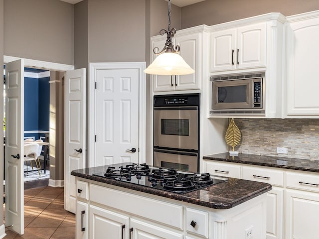 kitchen featuring tile patterned flooring, hanging light fixtures, stainless steel appliances, white cabinets, and decorative backsplash