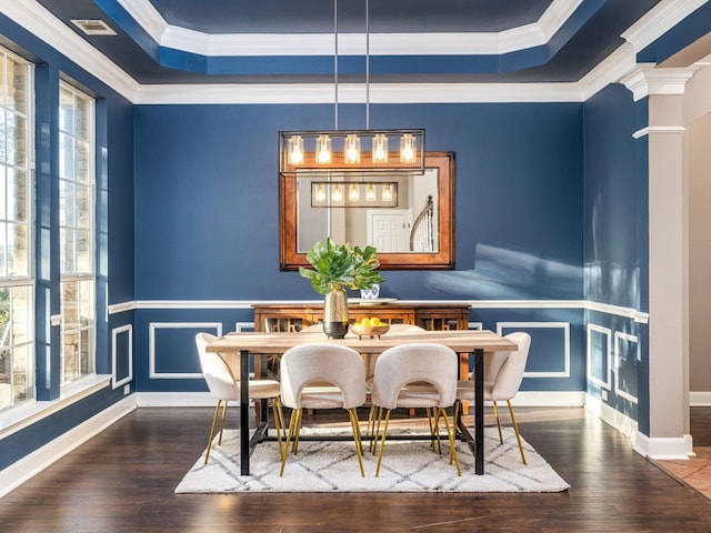 dining area featuring dark wood-type flooring, plenty of natural light, decorative columns, and a raised ceiling