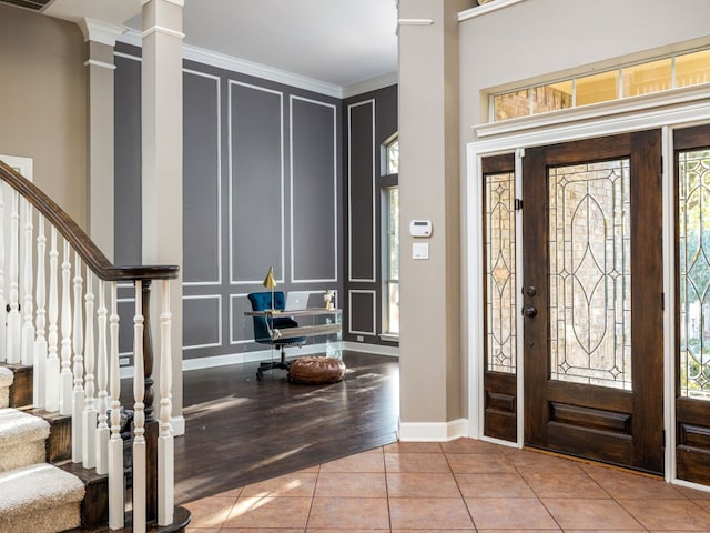 foyer entrance featuring ornamental molding, tile patterned flooring, and ornate columns