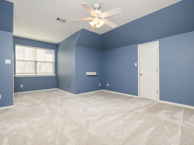 empty room with ceiling fan, light colored carpet, and vaulted ceiling