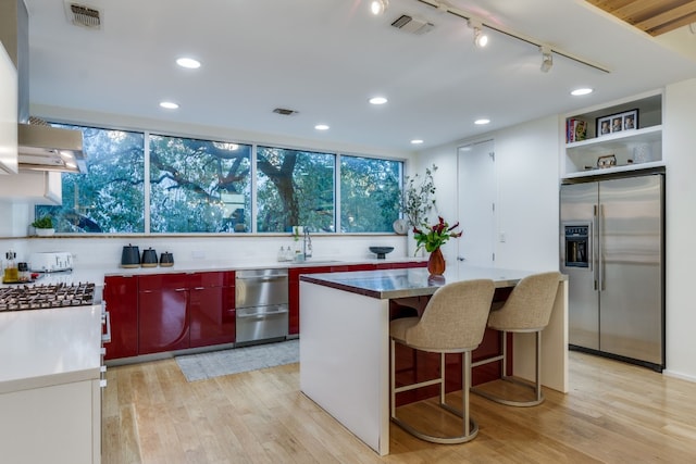 kitchen featuring extractor fan, tasteful backsplash, stainless steel fridge with ice dispenser, light hardwood / wood-style flooring, and a kitchen island