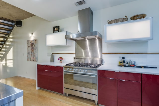 kitchen with light hardwood / wood-style flooring, backsplash, ventilation hood, and stainless steel range with gas stovetop