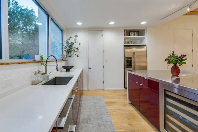 kitchen featuring sink, dishwashing machine, stainless steel fridge, beverage cooler, and light hardwood / wood-style flooring