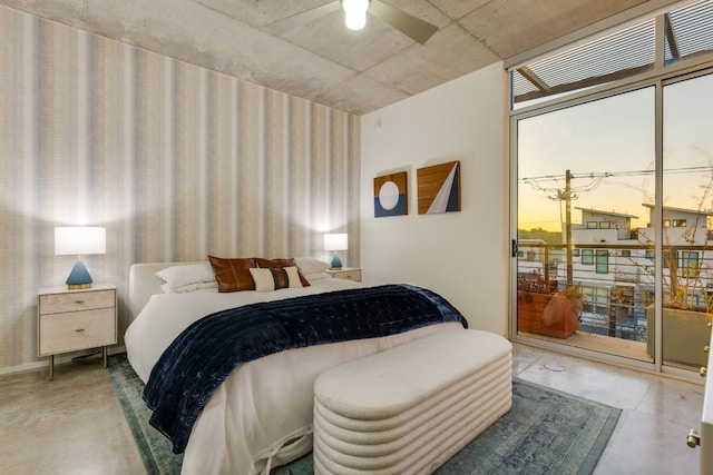 bedroom featuring ceiling fan, access to outside, concrete floors, and expansive windows