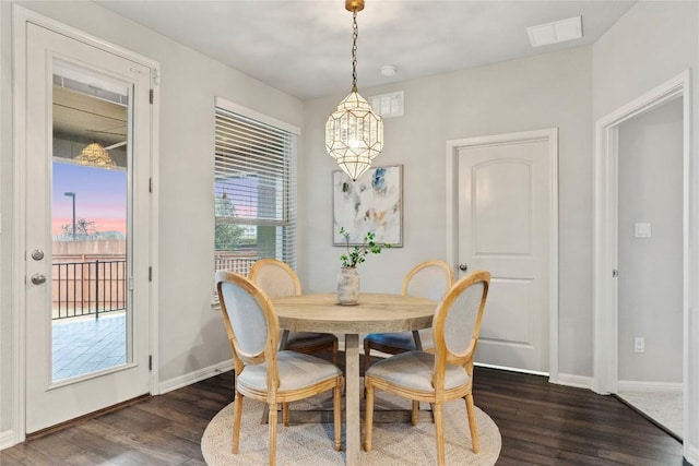 dining room with dark wood-type flooring and a chandelier