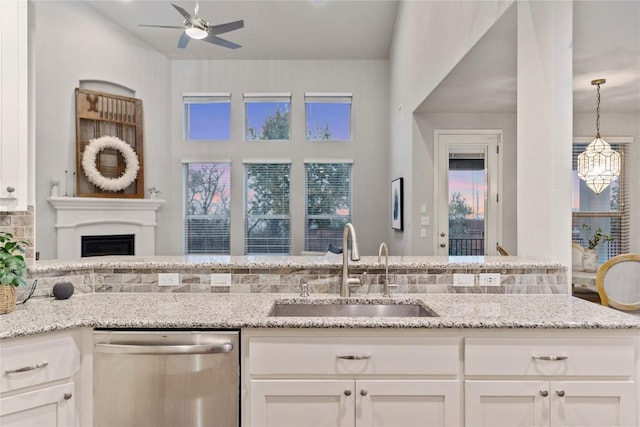 kitchen featuring light stone counters, sink, stainless steel dishwasher, and white cabinets