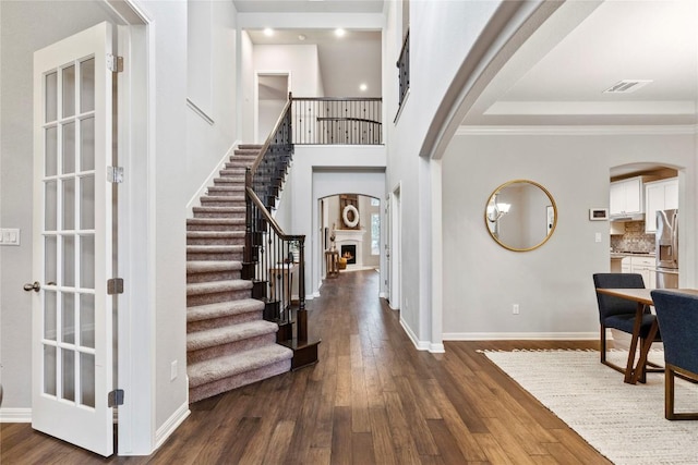 entrance foyer with crown molding, a towering ceiling, and dark hardwood / wood-style flooring