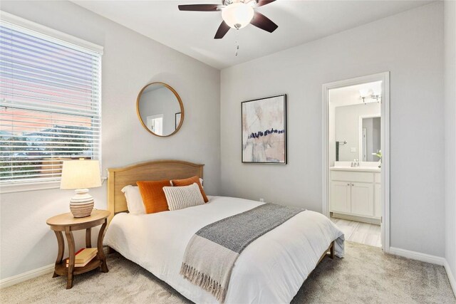 carpeted bedroom with ensuite bathroom, sink, and ceiling fan