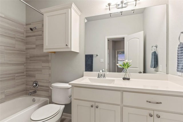 full bathroom featuring tiled shower / bath, vanity, and toilet