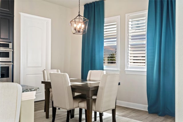 dining space with hardwood / wood-style floors and a notable chandelier