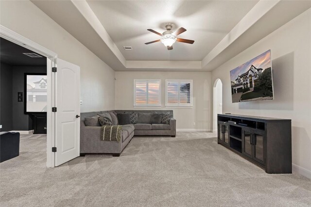 living room with light carpet, ceiling fan, and a tray ceiling