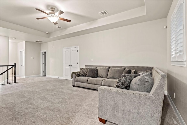 living room with carpet flooring, ceiling fan, and a tray ceiling