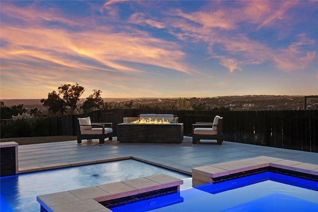 pool at dusk with an in ground hot tub, a patio area, and a fire pit