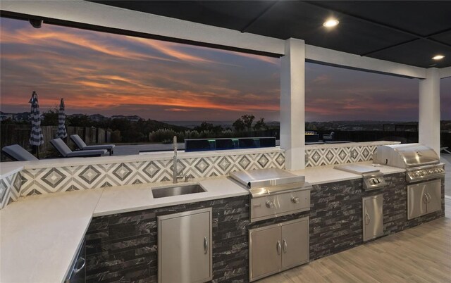 patio terrace at dusk featuring a grill, exterior kitchen, and sink