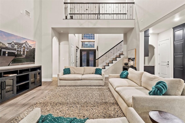 2513 Long Lasso Pass, Leander, TX 78641 - living room with arched walkways, wood finished floors, a high ceiling, stairs, and recessed lighting