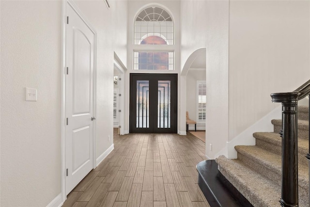 2513 Long Lasso Pass, Leander, TX 78641 - entrance foyer with arched walkways, wood finished floors, stairs, a high ceiling, and plenty of natural light