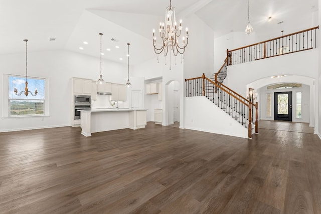 unfurnished living room with an inviting chandelier, sink, and dark wood-type flooring