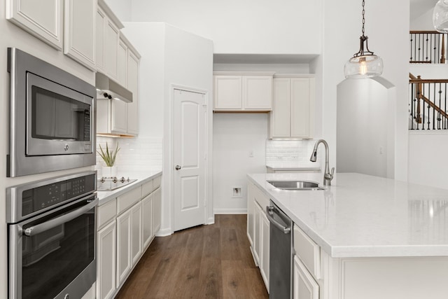 kitchen with appliances with stainless steel finishes, pendant lighting, sink, white cabinets, and light stone counters