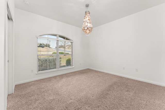 empty room featuring carpet flooring and a chandelier