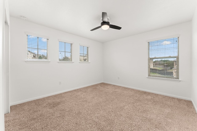 carpeted spare room featuring a wealth of natural light and ceiling fan