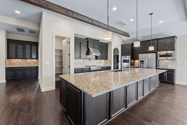 kitchen with decorative light fixtures, sink, a large island with sink, stainless steel appliances, and beam ceiling