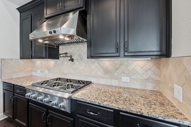 kitchen with light stone counters, stainless steel gas stovetop, and range hood