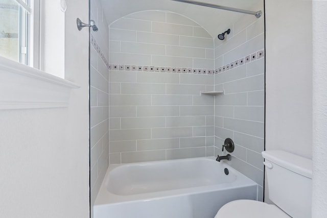 bathroom with tiled shower / bath combo and toilet