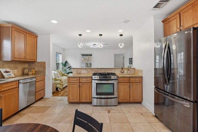 kitchen featuring tasteful backsplash, decorative light fixtures, appliances with stainless steel finishes, kitchen peninsula, and light stone countertops