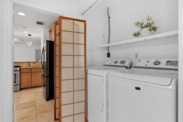 clothes washing area with washing machine and clothes dryer and light tile patterned floors