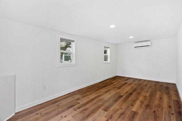 spare room with dark hardwood / wood-style floors and an AC wall unit