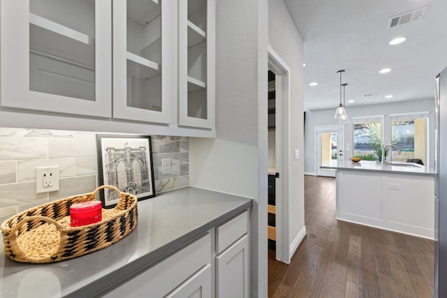 kitchen with sink, dark wood-type flooring, white cabinetry, hanging light fixtures, and tasteful backsplash