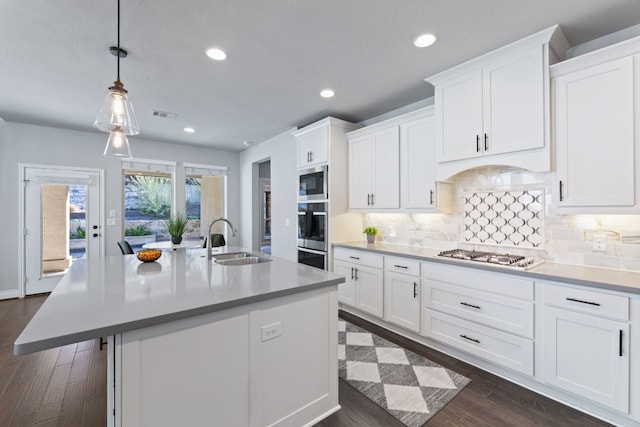 kitchen featuring white cabinetry, stainless steel appliances, and an island with sink