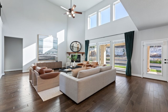 living room featuring dark hardwood / wood-style floors, a healthy amount of sunlight, and a stone fireplace