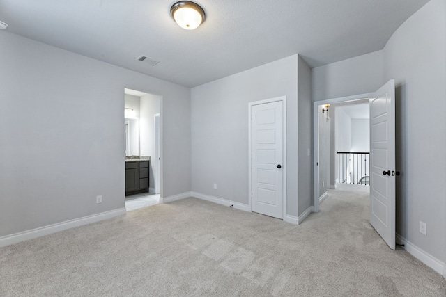 unfurnished bedroom featuring connected bathroom and light colored carpet