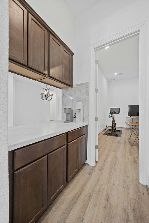 bar featuring a notable chandelier, dark brown cabinetry, and light hardwood / wood-style floors