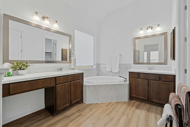 bathroom with tiled tub, vanity, and wood-type flooring