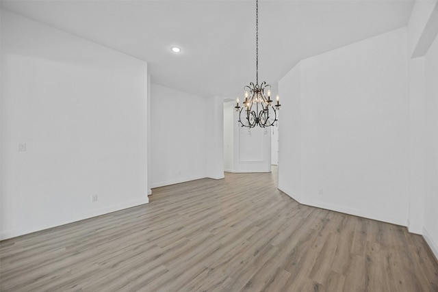 unfurnished dining area with a notable chandelier and light hardwood / wood-style flooring