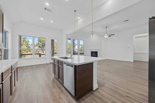 kitchen featuring pendant lighting, sink, dishwasher, a kitchen island with sink, and light wood-type flooring