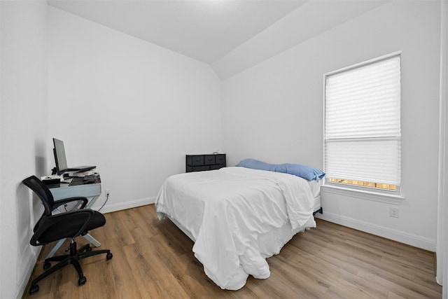 bedroom with lofted ceiling and wood-type flooring