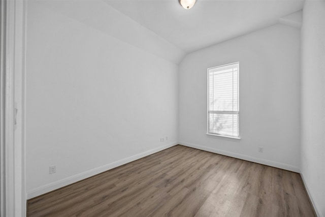 empty room featuring wood-type flooring and vaulted ceiling