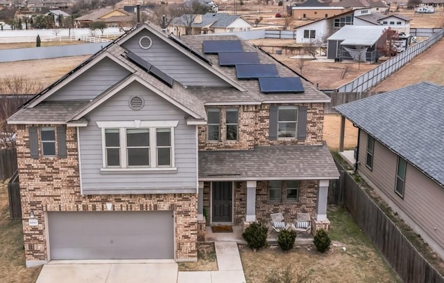 view of front of property featuring a garage, covered porch, and solar panels