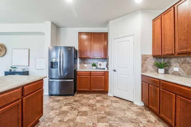 kitchen with light stone countertops, stainless steel fridge, and backsplash