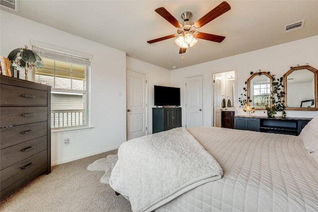 bedroom with ceiling fan, connected bathroom, and light carpet