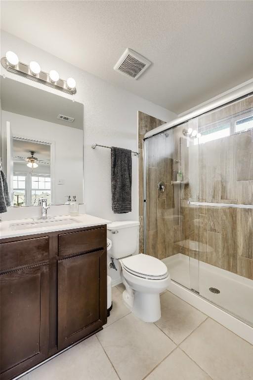 bathroom featuring vanity, toilet, tile patterned floors, and walk in shower