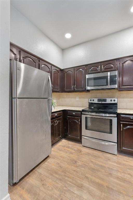 kitchen featuring backsplash, dark brown cabinets, stainless steel appliances, and light hardwood / wood-style floors