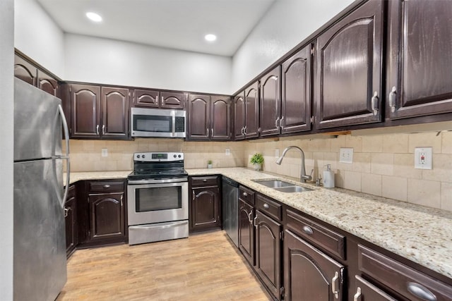 kitchen with dark brown cabinetry, sink, light wood-type flooring, appliances with stainless steel finishes, and decorative backsplash